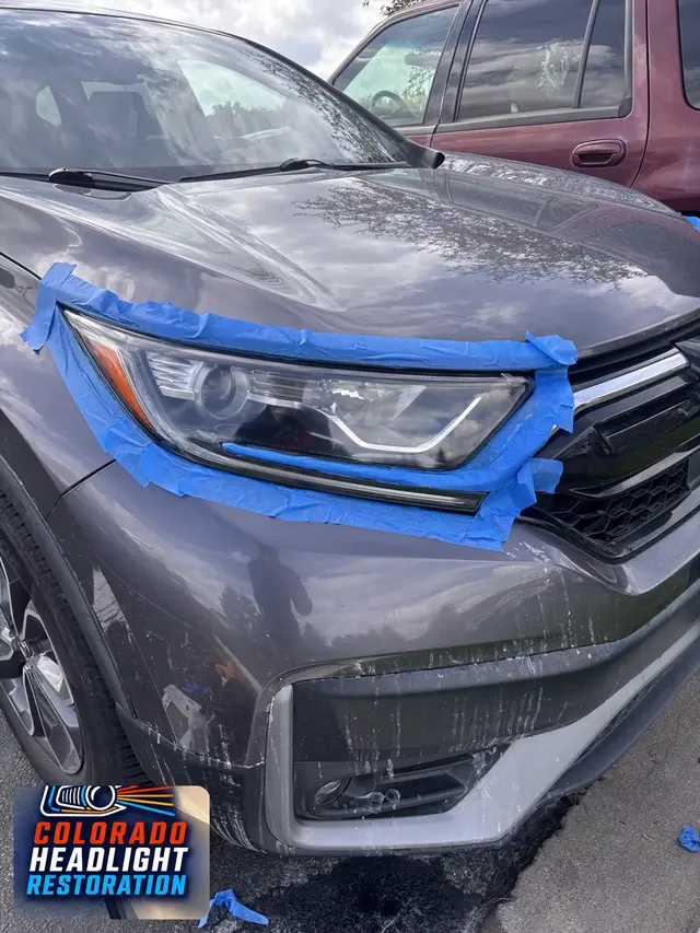 Gray SUV headlight with protective masking during restoration