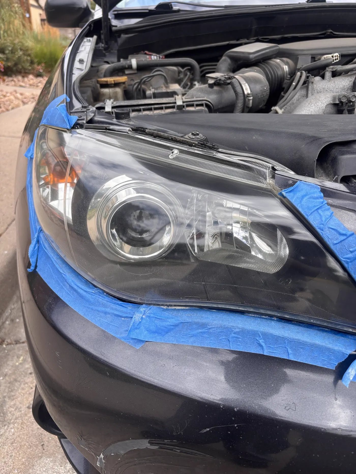 Gray car headlight with blue protective masking tape