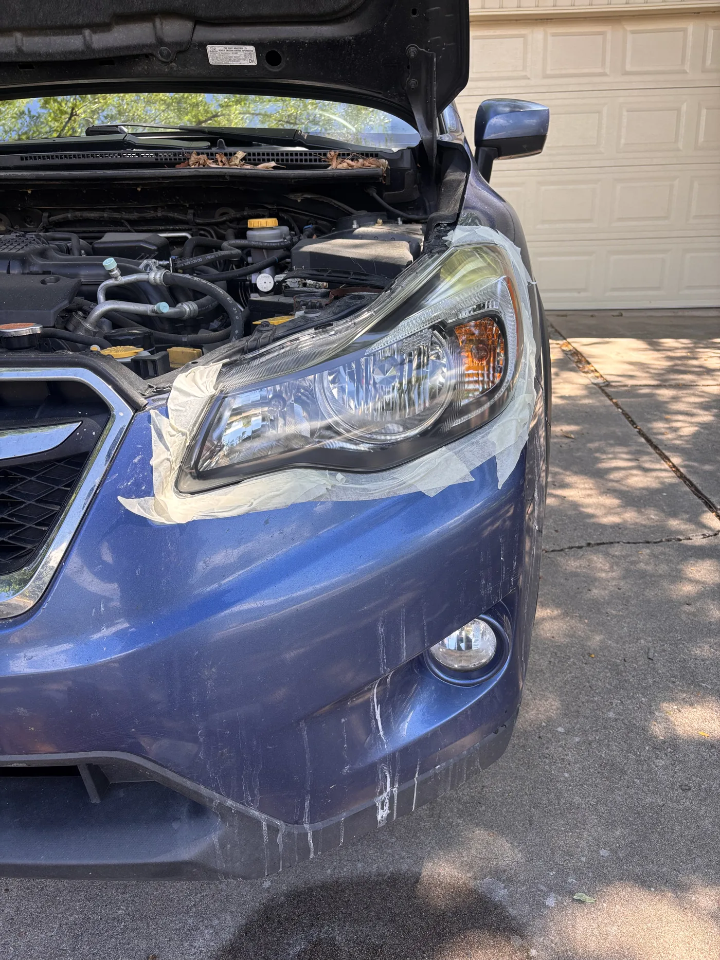 Blue sedan headlight with hood raised before restoration